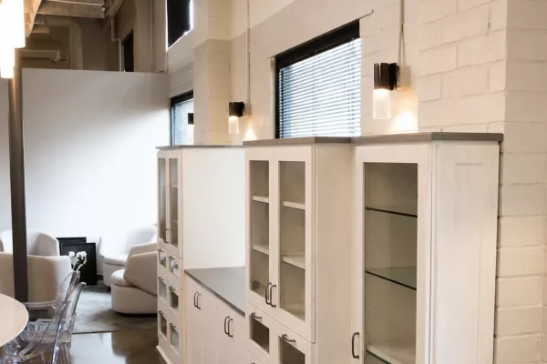 Custom built-in storage cabinetry with glass-front doors and quartz countertops in a modern loft office by TopSouth Countertops and Closets in Atlanta, GA