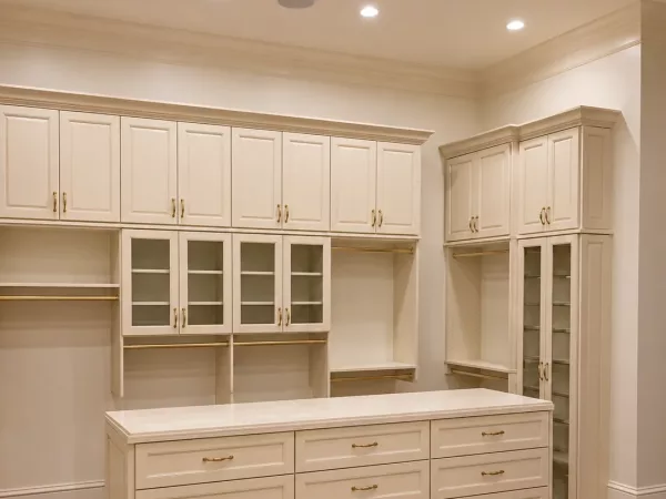 Custom closet cabinetry with glass-front doors and a quartz-topped drawer island by TopSouth Countertops and Closets in Marietta, GA