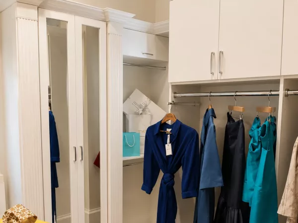 Walk-in closet with mirrored cabinet doors and custom hanging storage by TopSouth Countertops and Closets in Marietta, GA