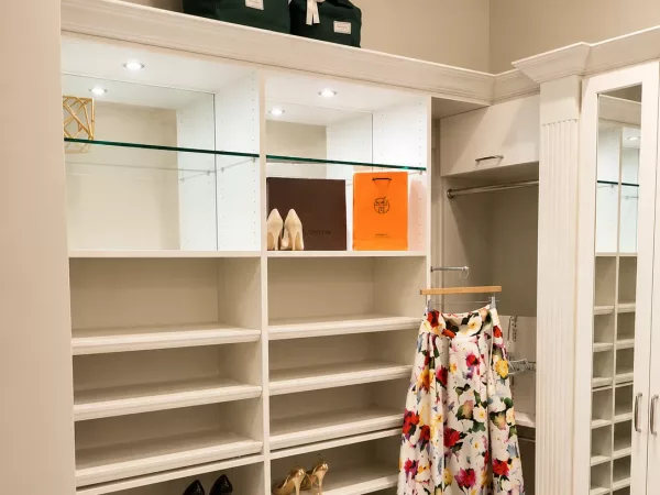 Walk-in closet with adjustable shoe shelving and a lighted glass display shelf by TopSouth Countertops and Closets in Atlanta, GA