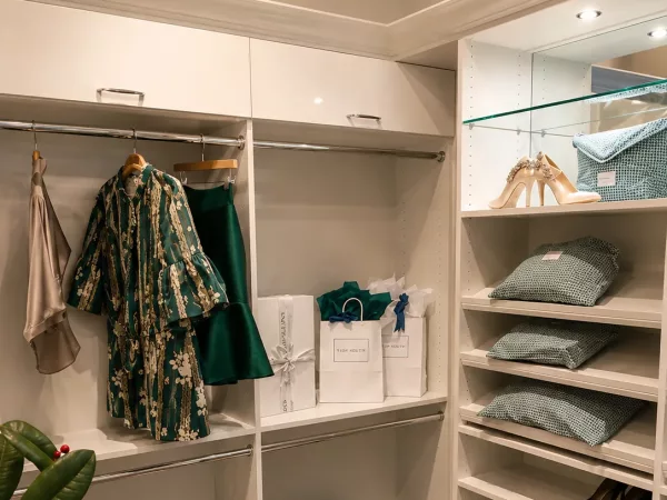 White walk-in closet with corner hanging storage and tiered shoe shelving by TopSouth Countertops and Closets in Marietta, GA