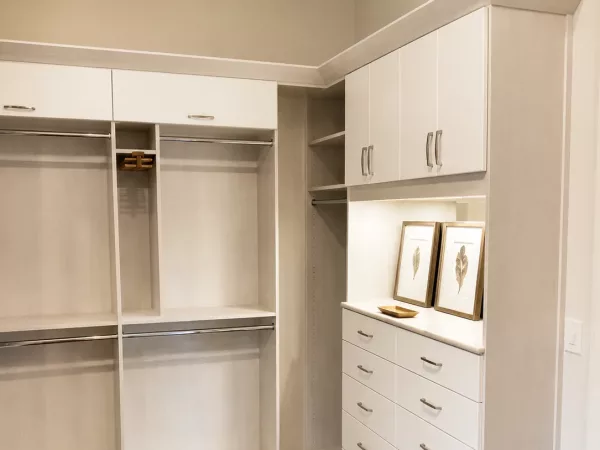White wood-grain closet system with double hanging sections and a built-in drawer tower by TopSouth Countertops and Closets in Atlanta, GA